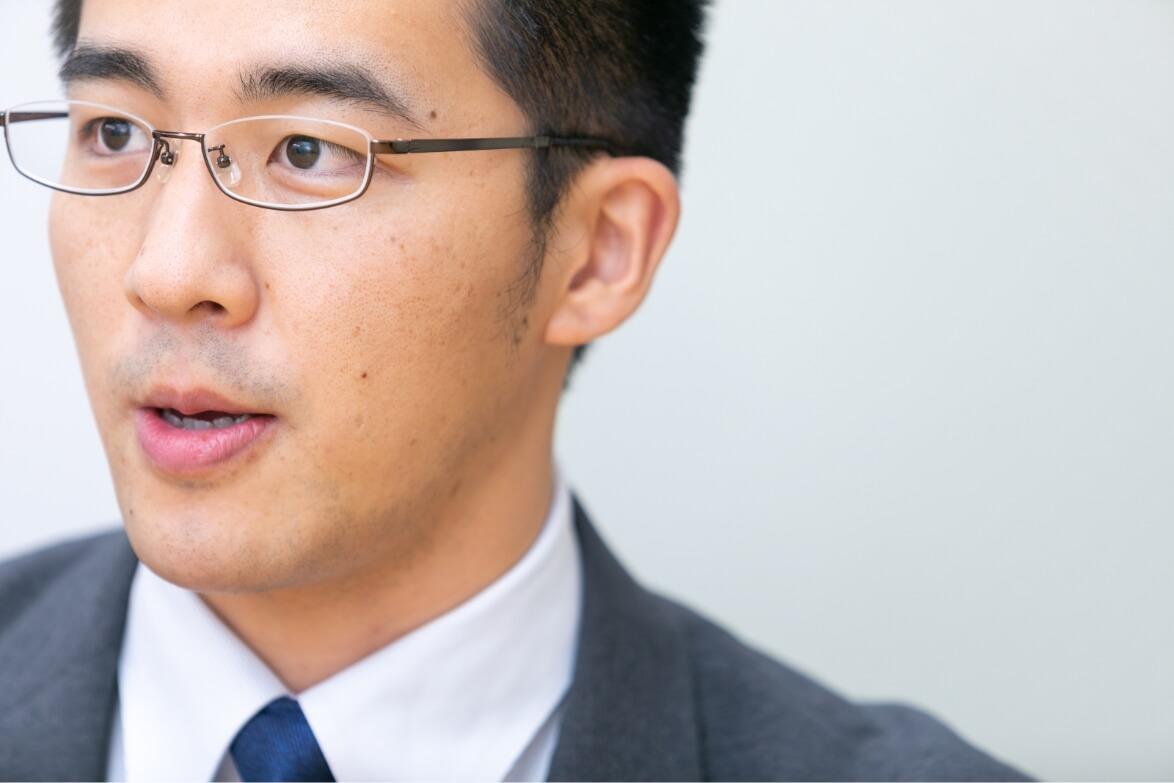 インタビューに真剣な眼差しで答える長野県信連証券運用の男性職員の横顔