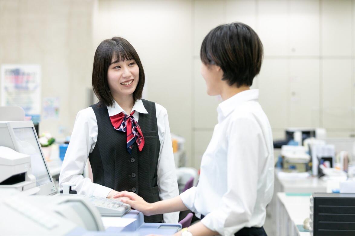 両替機の前で、部下女性職員と話す長野県信連貯金為替の女性職員