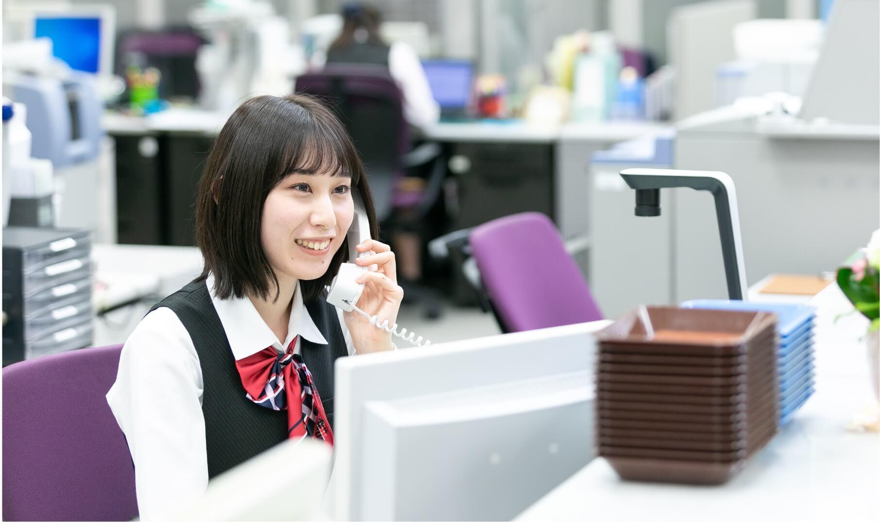 窓口に座りながら電話応対をしている長野県信連の女性職員